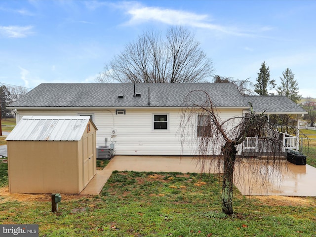 rear view of property with a yard, central AC unit, and a storage unit