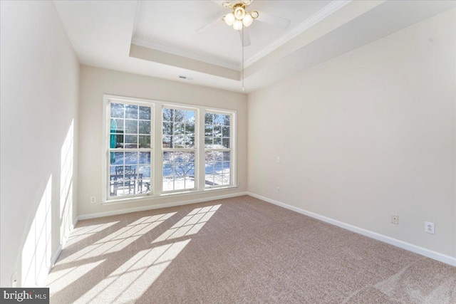 empty room with light carpet, a tray ceiling, ceiling fan, and crown molding