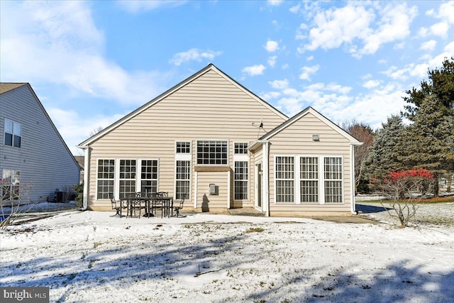 snow covered rear of property with central AC unit