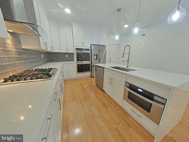 kitchen with sink, white cabinets, light hardwood / wood-style floors, and wall chimney range hood