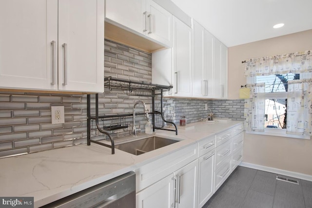 kitchen with sink, stainless steel dishwasher, tasteful backsplash, light stone counters, and white cabinetry