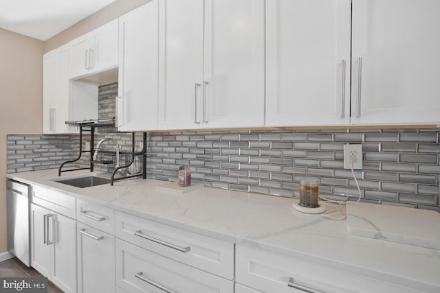 kitchen with dishwasher, sink, light stone countertops, tasteful backsplash, and white cabinetry