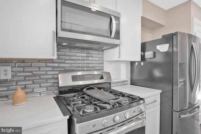 kitchen with decorative backsplash, white cabinets, stainless steel appliances, and light stone counters