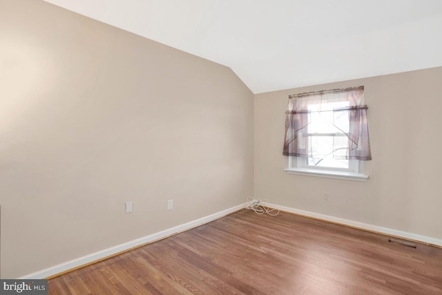 empty room featuring hardwood / wood-style floors and lofted ceiling