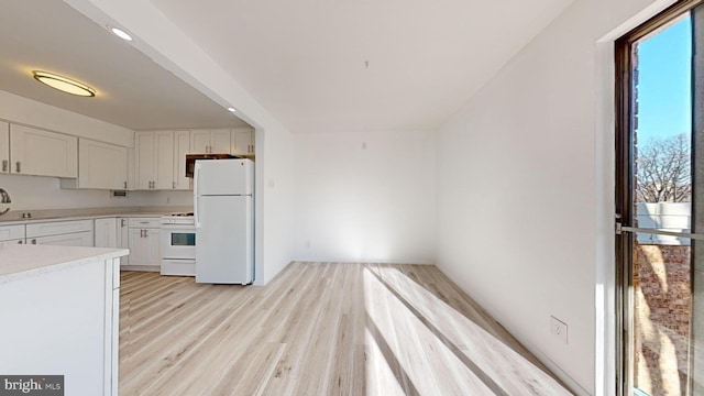 kitchen with white cabinetry, light hardwood / wood-style flooring, white appliances, and sink