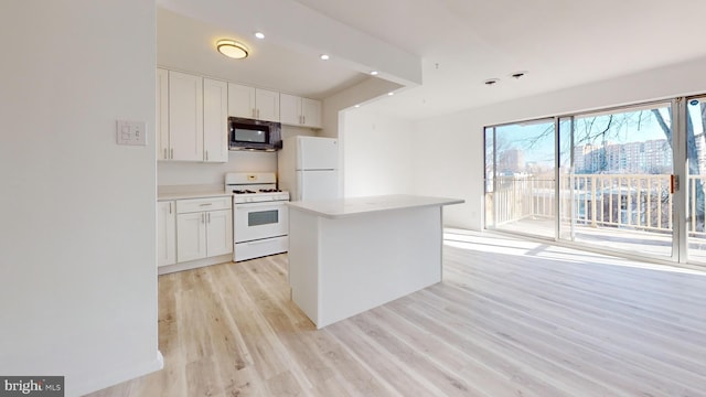 kitchen featuring white cabinetry, a kitchen island, white appliances, and light wood-type flooring