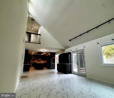 interior space featuring french doors, rail lighting, and lofted ceiling