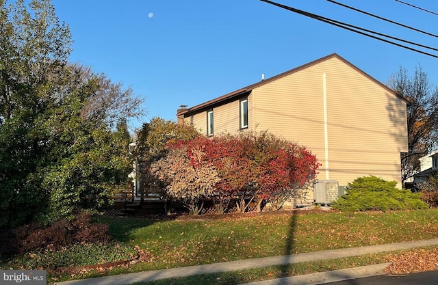 view of side of property featuring a lawn and central AC