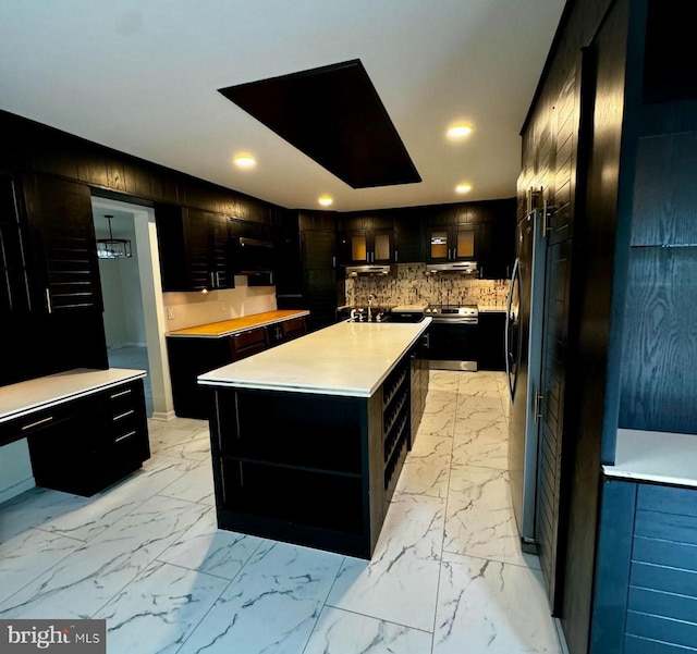 kitchen with appliances with stainless steel finishes, a center island with sink, tasteful backsplash, and wood walls