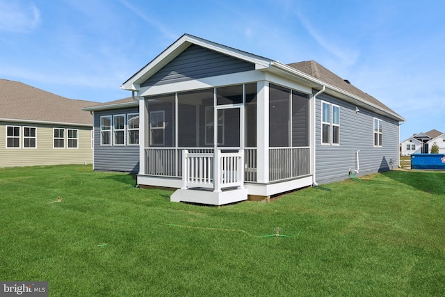 back of property with a sunroom and a yard