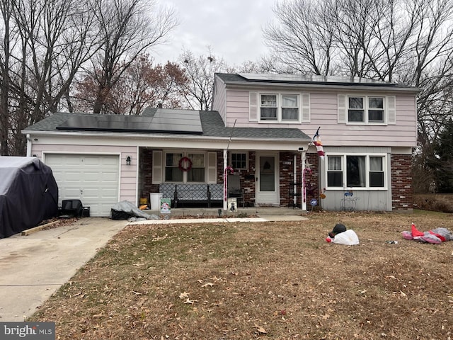 front of property featuring a front yard, a porch, solar panels, and a garage