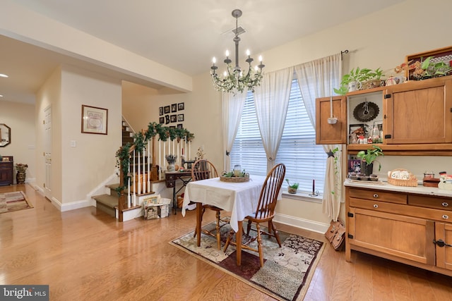 dining area featuring light wood-style flooring, a chandelier, stairway, and baseboards