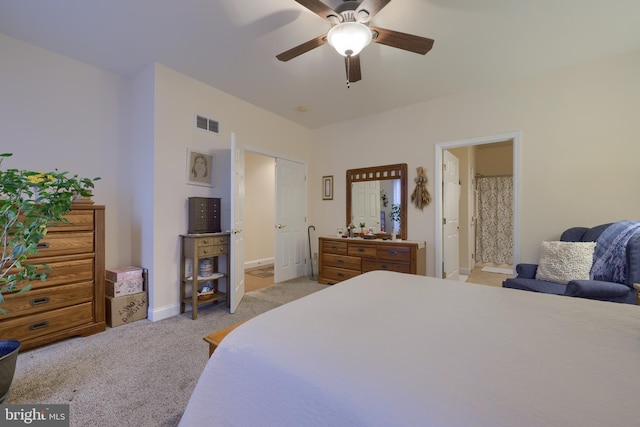 bedroom with visible vents, ensuite bathroom, a ceiling fan, light carpet, and baseboards