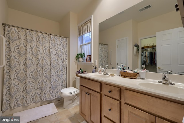 bathroom featuring double vanity, visible vents, toilet, and a sink