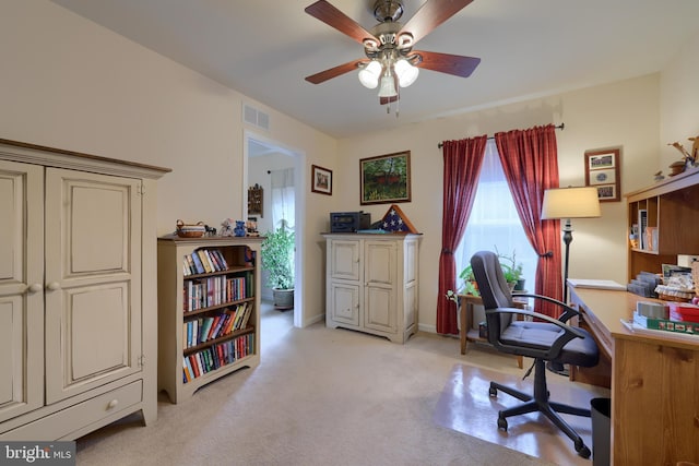 office space featuring a ceiling fan, visible vents, light carpet, and baseboards