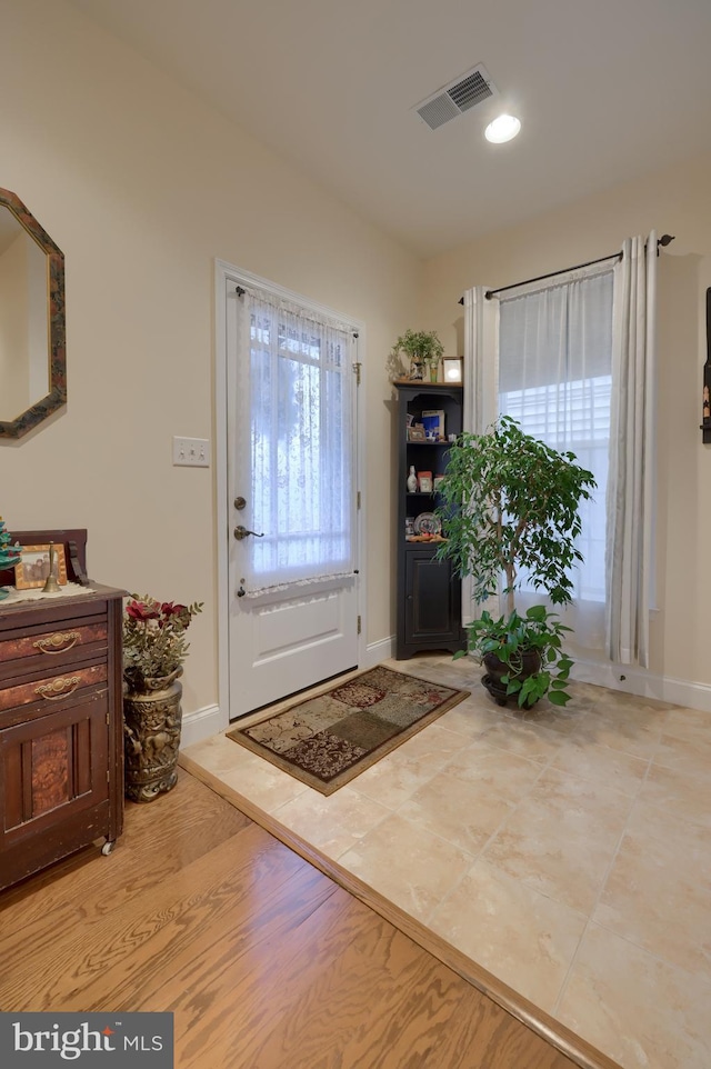 foyer entrance with light wood-type flooring, visible vents, and baseboards