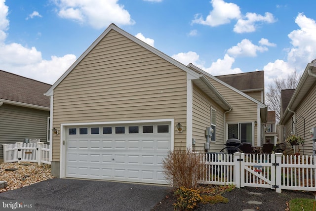 view of front facade with a garage, driveway, a gate, and fence