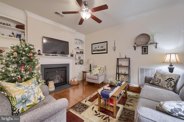 living room featuring built in shelves, visible vents, ceiling fan, and a fireplace with flush hearth