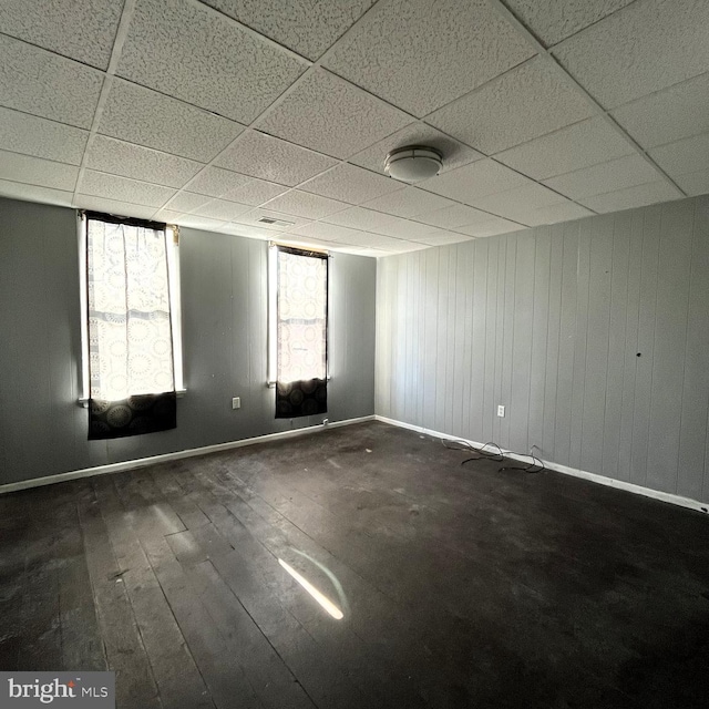 unfurnished room featuring a paneled ceiling and dark hardwood / wood-style floors