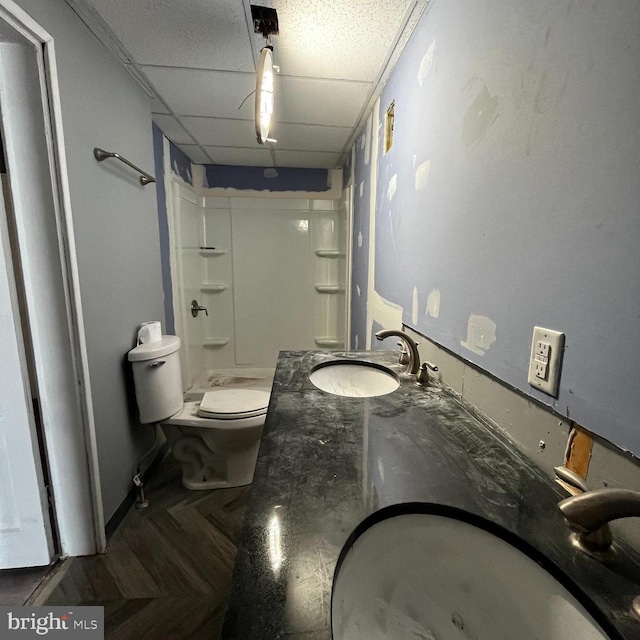 bathroom featuring a paneled ceiling, sink, and toilet