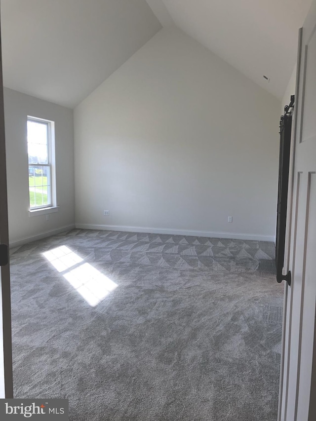 empty room with dark carpet and lofted ceiling