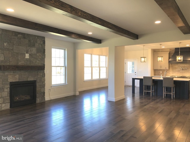 unfurnished living room featuring a fireplace, beamed ceiling, and dark wood-type flooring