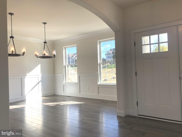 foyer entrance with crown molding, dark hardwood / wood-style flooring, and an inviting chandelier