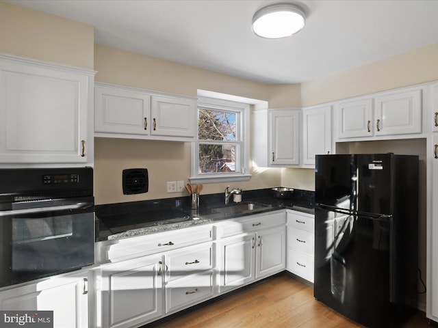 kitchen with sink, white cabinetry, dark stone counters, and black appliances