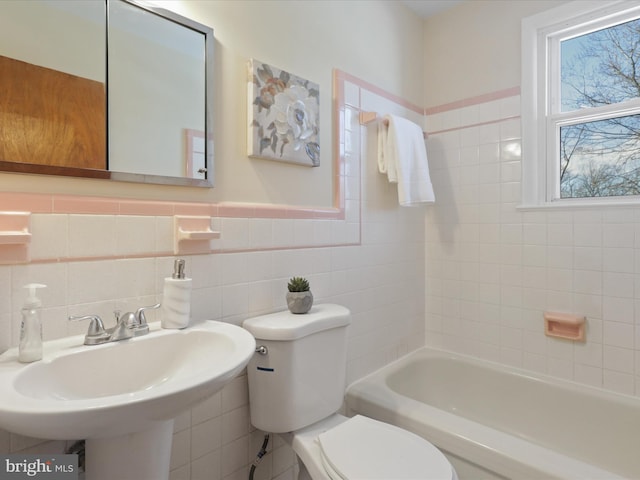 bathroom with a bathtub, toilet, tile walls, and sink