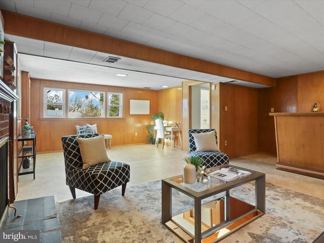 living room featuring a brick fireplace and wooden walls