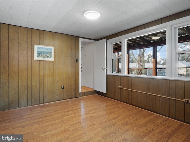 unfurnished room featuring light hardwood / wood-style flooring and wooden walls