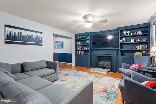 living room with a fireplace, light hardwood / wood-style flooring, and ceiling fan