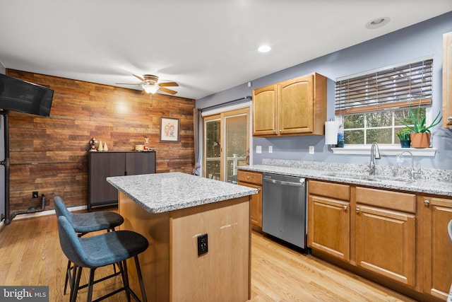 kitchen featuring sink, a kitchen island, stainless steel dishwasher, and light hardwood / wood-style floors