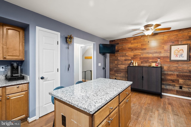 kitchen with wooden walls, a kitchen island, and wood-type flooring