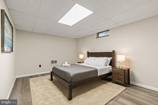 bedroom featuring light wood-type flooring and a drop ceiling