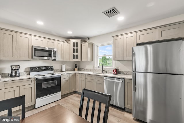 kitchen featuring light hardwood / wood-style flooring, stainless steel appliances, light stone counters, and sink