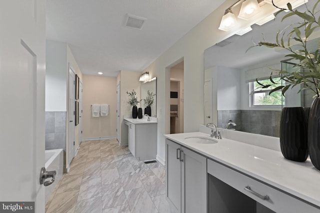 bathroom with a tub and vanity