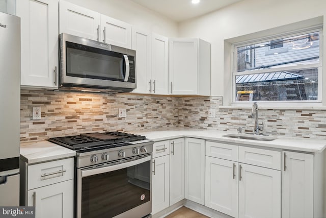 kitchen featuring appliances with stainless steel finishes, backsplash, white cabinetry, and sink