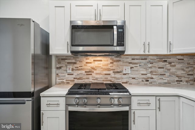 kitchen with tasteful backsplash, white cabinetry, light stone countertops, and stainless steel appliances