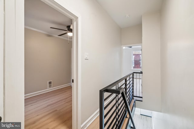 hallway featuring ornamental molding and light wood-type flooring