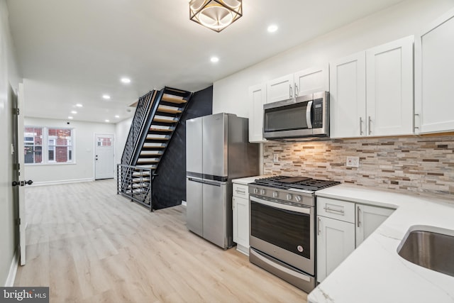 kitchen featuring light wood-type flooring, white cabinetry, stainless steel appliances, and tasteful backsplash