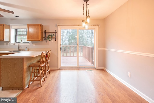 unfurnished dining area with light wood-type flooring, ceiling fan, and sink