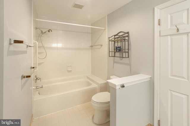 bathroom featuring tile patterned flooring, tiled shower / bath combo, and toilet