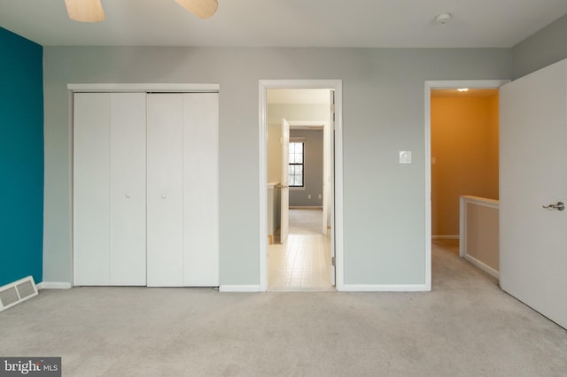 unfurnished bedroom featuring ceiling fan, a closet, and light colored carpet