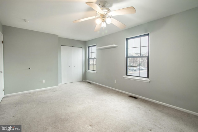 unfurnished bedroom featuring ceiling fan, light colored carpet, and a closet