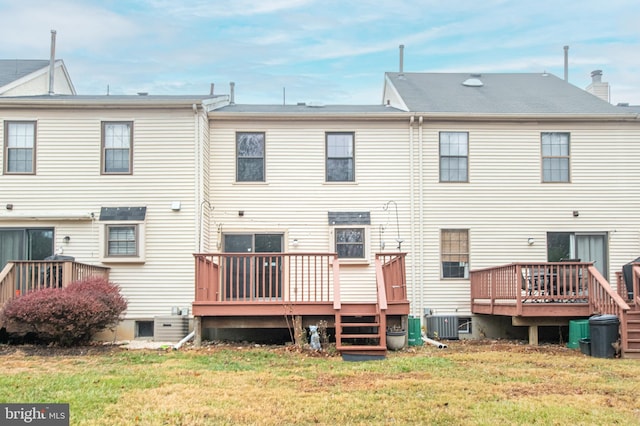 back of property with a deck, a yard, and central AC