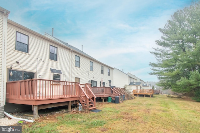 rear view of property featuring a deck and a lawn