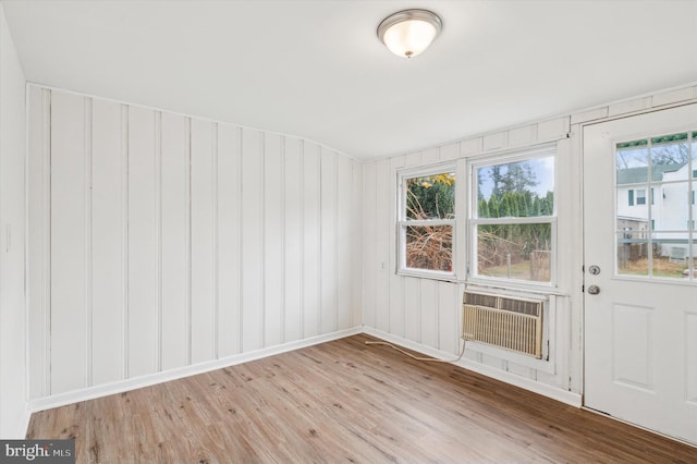 spare room with a wall unit AC, plenty of natural light, and light hardwood / wood-style floors