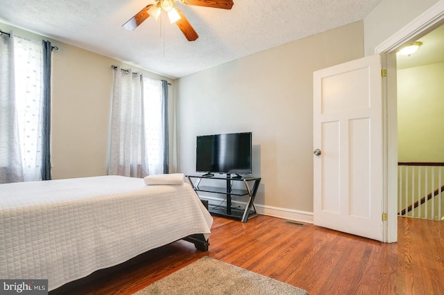 bedroom featuring hardwood / wood-style floors, ceiling fan, and a textured ceiling