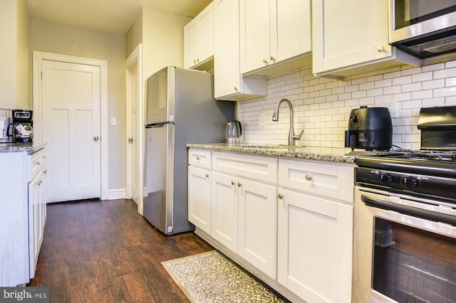 kitchen featuring dark wood-type flooring, white cabinets, sink, light stone countertops, and appliances with stainless steel finishes